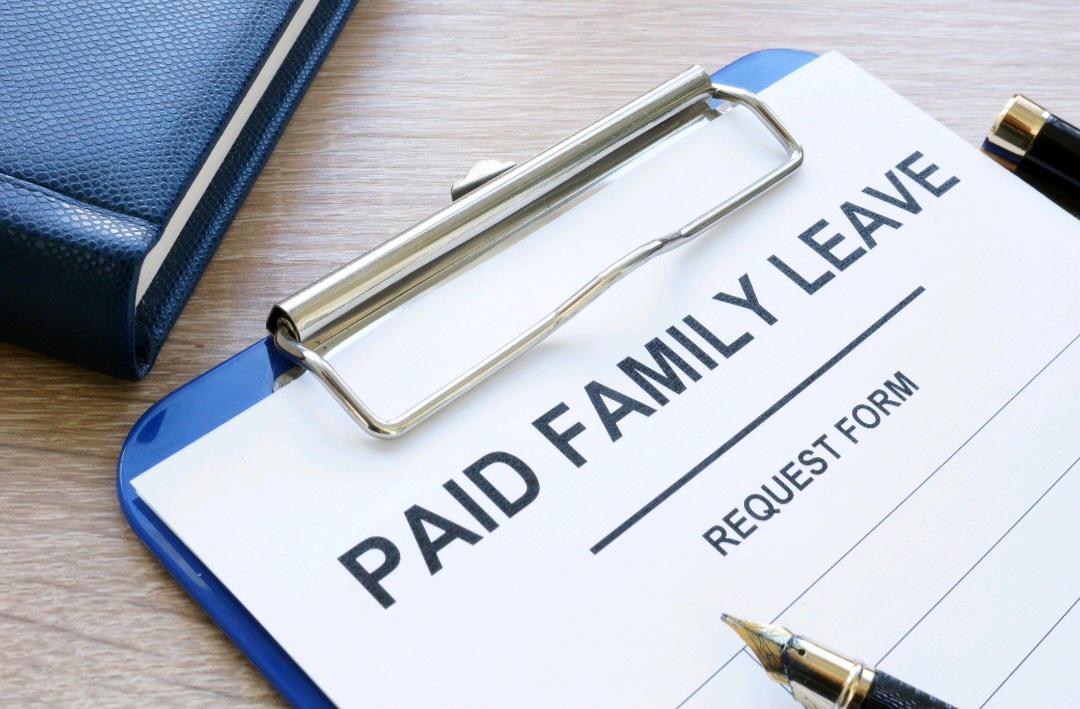 Paid family leave form in clipboard and note pad.